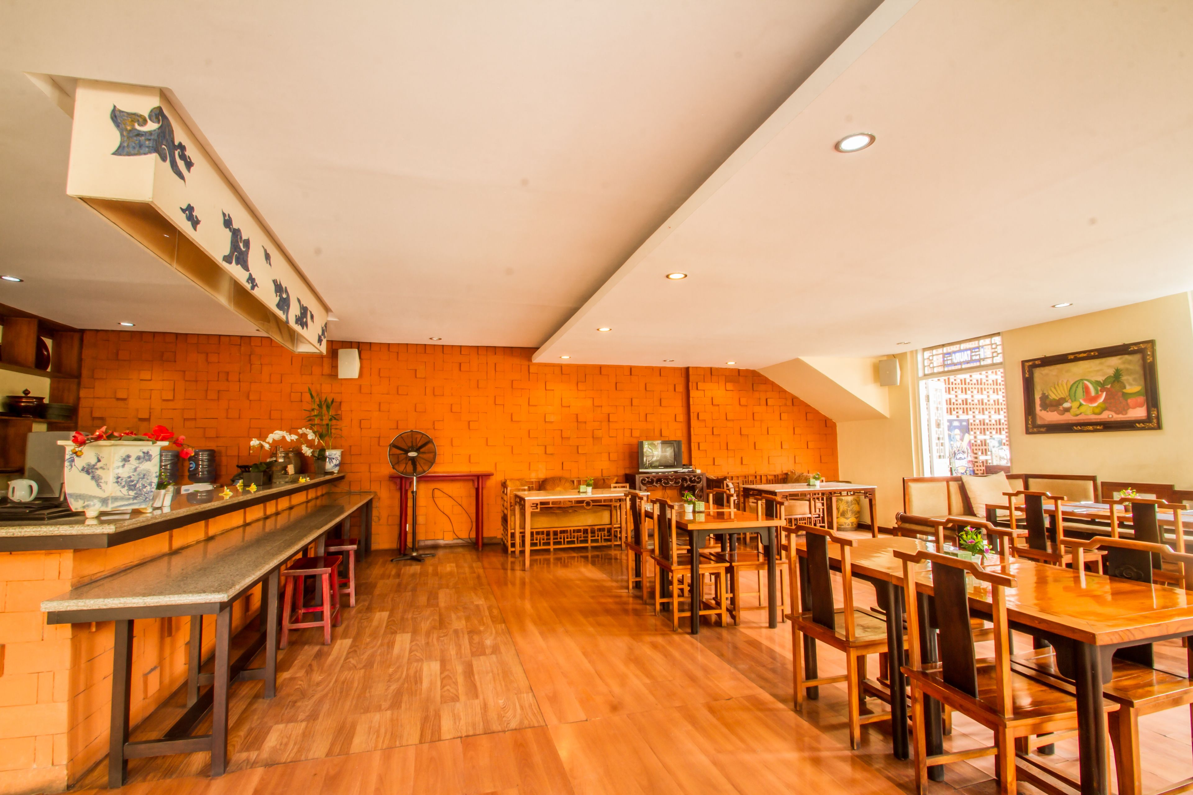Un restaurant avec des tables et des chaises en bois, un comptoir où est affiché le menu, et un téléviseur.