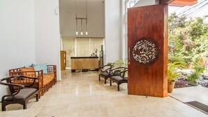 Un vestíbulo amplio con una recepción, muebles de madera y vistas al exterior.
