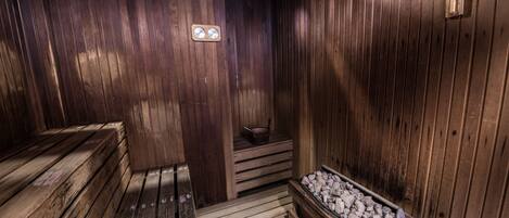 A wooden sauna with benches and a stone basin.