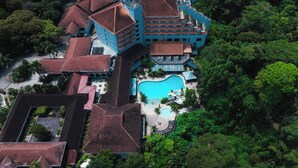 An aerial view of a resort with multiple buildings, a swimming pool, and lush greenery surrounding the property.