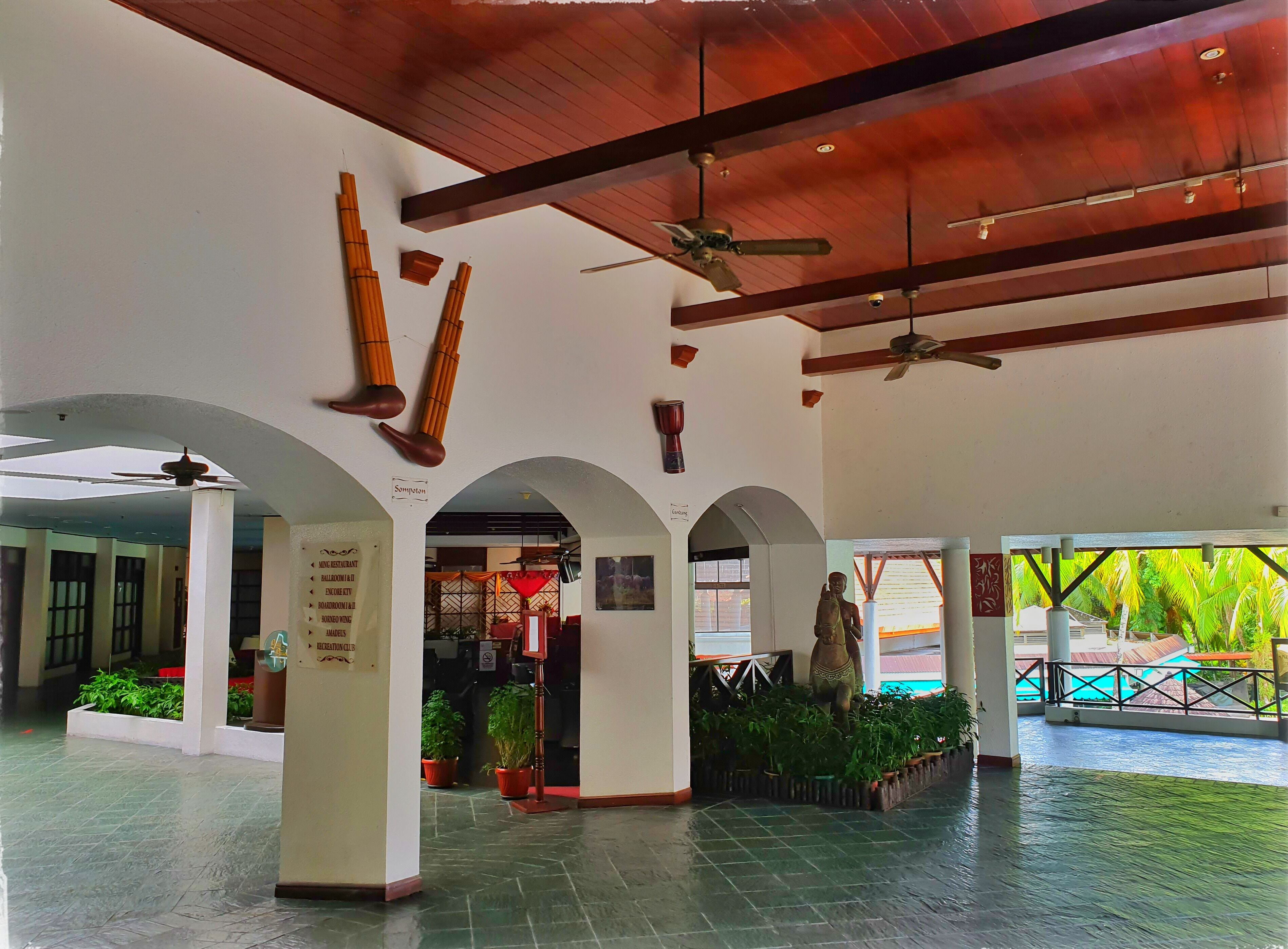 A spacious lobby with high ceilings, multiple ceiling fans, and a central statue.