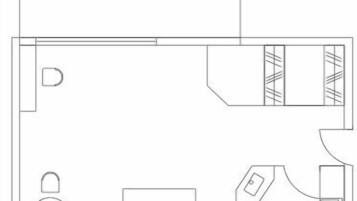 A floor plan of a hotel room with a balcony, a bed, a small table, a chair, and a bathroom.