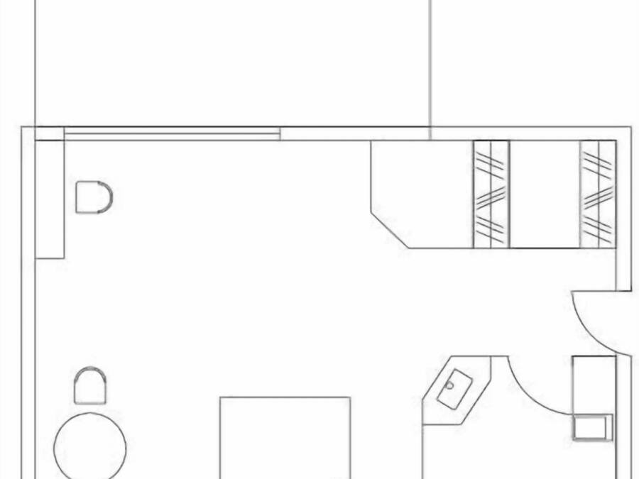 A floor plan of a hotel room with a balcony, a bed, a small table, a chair, and a bathroom.
