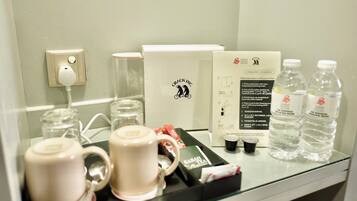 A hotel minibar with coffee-making equipment, water bottles, and tea packets.