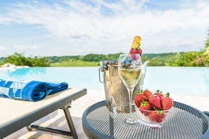 A table with a metal pitcher, a glass of white wine, and a bowl of strawberries.