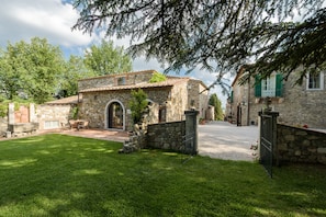 A stone building with a tiled roof, a paved driveway, and a well-maintained lawn.