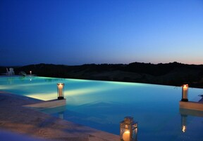 Una piscina al aire libre, una piscina con borde infinito, tumbonas