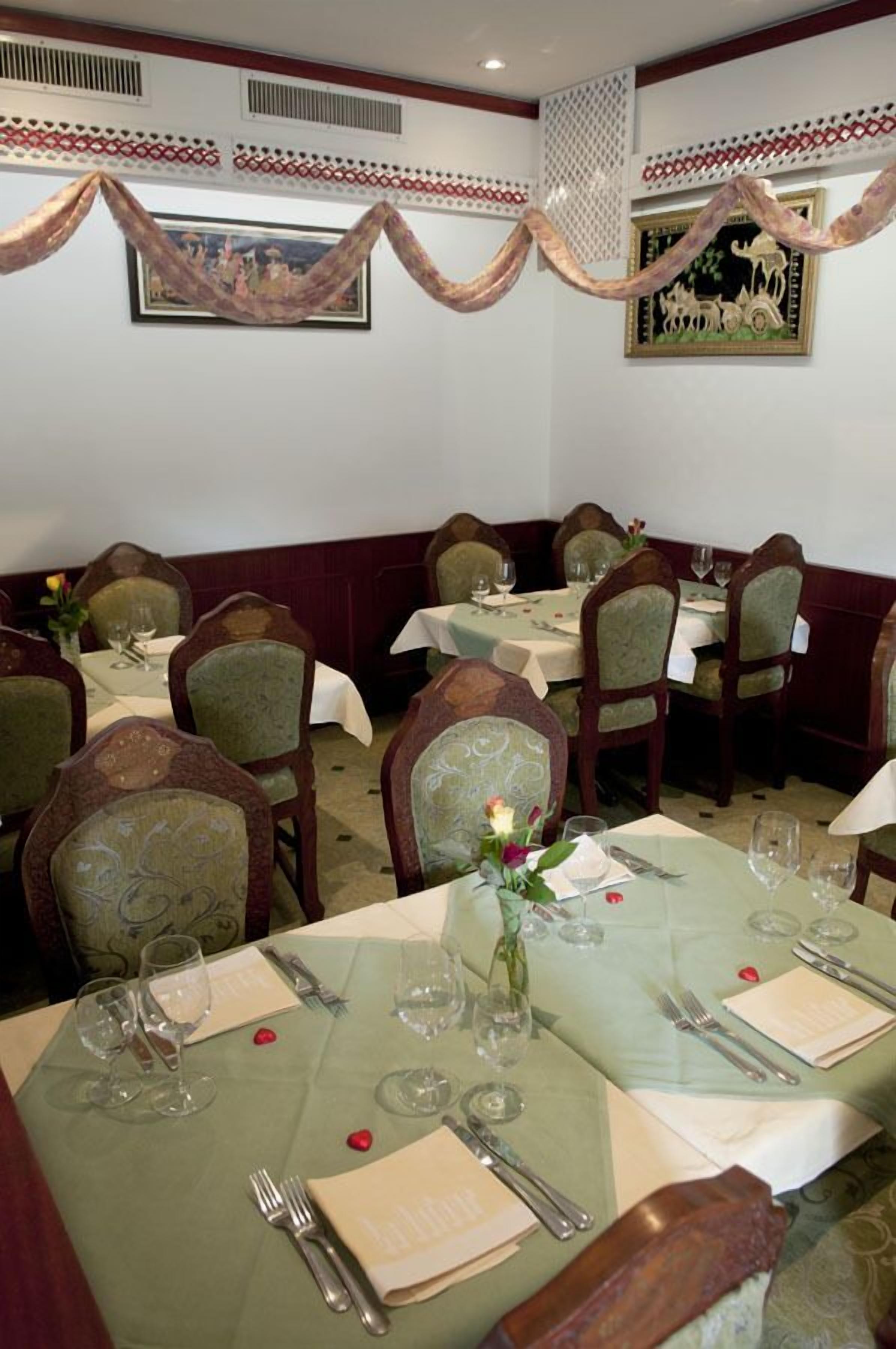 A restaurant with multiple tables set for dining, each with chairs and table settings including wine glasses and cutlery.