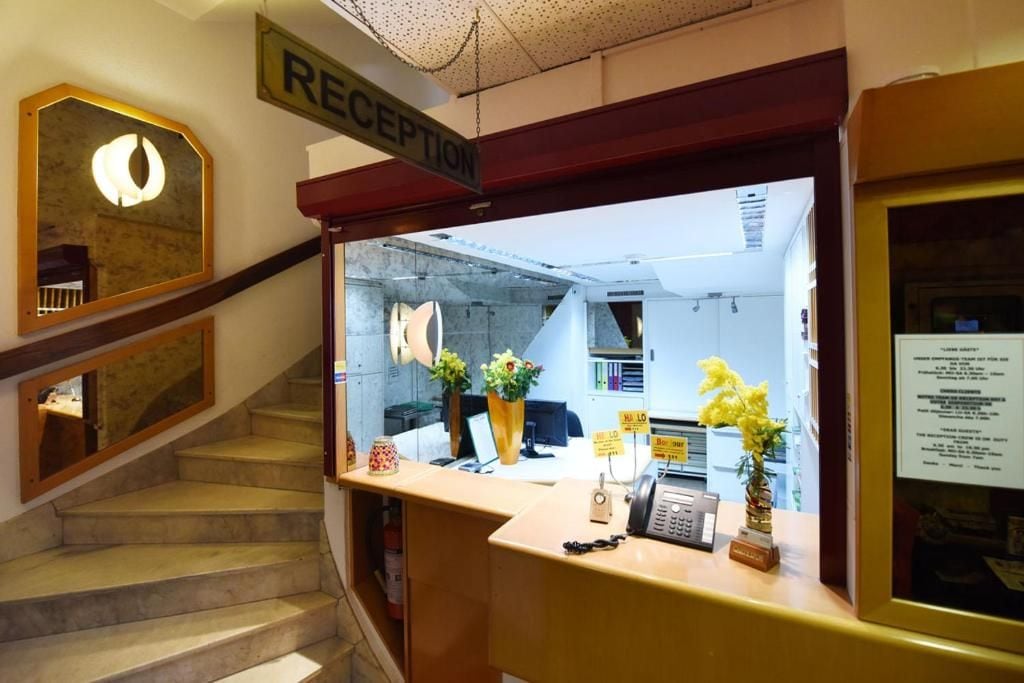 Een receptiegedeelte met een trap, een receptiebalie en een bord met de tekst receptie.