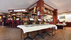 Un restaurant avec une longue table dressée pour le repas, entourée de chaises rouges.