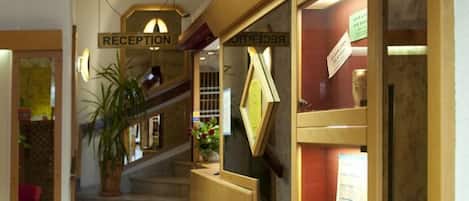 A reception area with a staircase, wooden reception desk, and framed pictures on the wall.