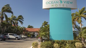 The Ocean View Hotel sign with a clear view of the surrounding palm trees and parked cars. - Ocean View Hotel (Campeche)