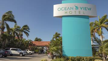 L’enseigne de l’hôtel Ocean View offre une vue dégagée sur les palmiers environnants et les voitures garées.