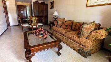 A living room with a wooden coffee table, patterned sofa, and a decorative vase.