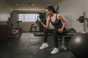 Un gimnasio con equipo de ejercicio, una banca y una pelota de ejercicio grande.