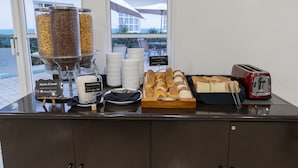 Un buffet per la colazione con cereali, latte e pasticceria.