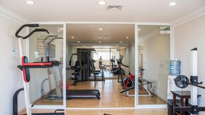 Una palestra con attrezzature cardio, macchinari per sollevamento pesi e uno specchio a parete.