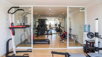 Une salle de sport équipée de machines de cardio, de postes d’entraînement en musculation et dotée d’un mur avec des miroirs.