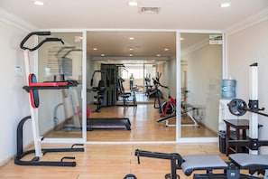 Una palestra con attrezzature cardio, macchinari per sollevamento pesi e uno specchio a parete.