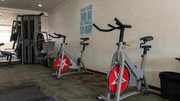 Uma academia com bicicletas ergométricas, esteira e aparelhos de musculação.