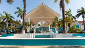 A covered pavilion with a pool, surrounded by palm trees and buildings. - Ocean View Hotel (Campeche)