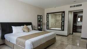 A hotel room with a large bed, a bathroom with a large mirror, and a separate bathroom with a shower. - Ocean View Hotel (Campeche)