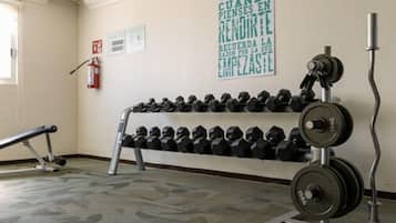 A gym with a wall-mounted rack of dumbbells and a barbell.
