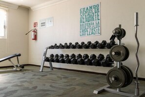 Una palestra con un porta pesi a parete e un bilanciere.