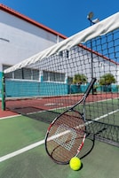 Una cancha de tenis con una red, una raqueta y una pelota.