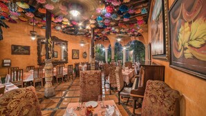 A restaurant with a checkered floor, ornate chairs, and a ceiling adorned with colorful paper flowers. - Hotel Posada del Hidalgo by Balderrama Hotel Collection (El Fuerte)