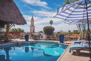 Una piscina al aire libre, sombrillas, sillones reclinables de piscina