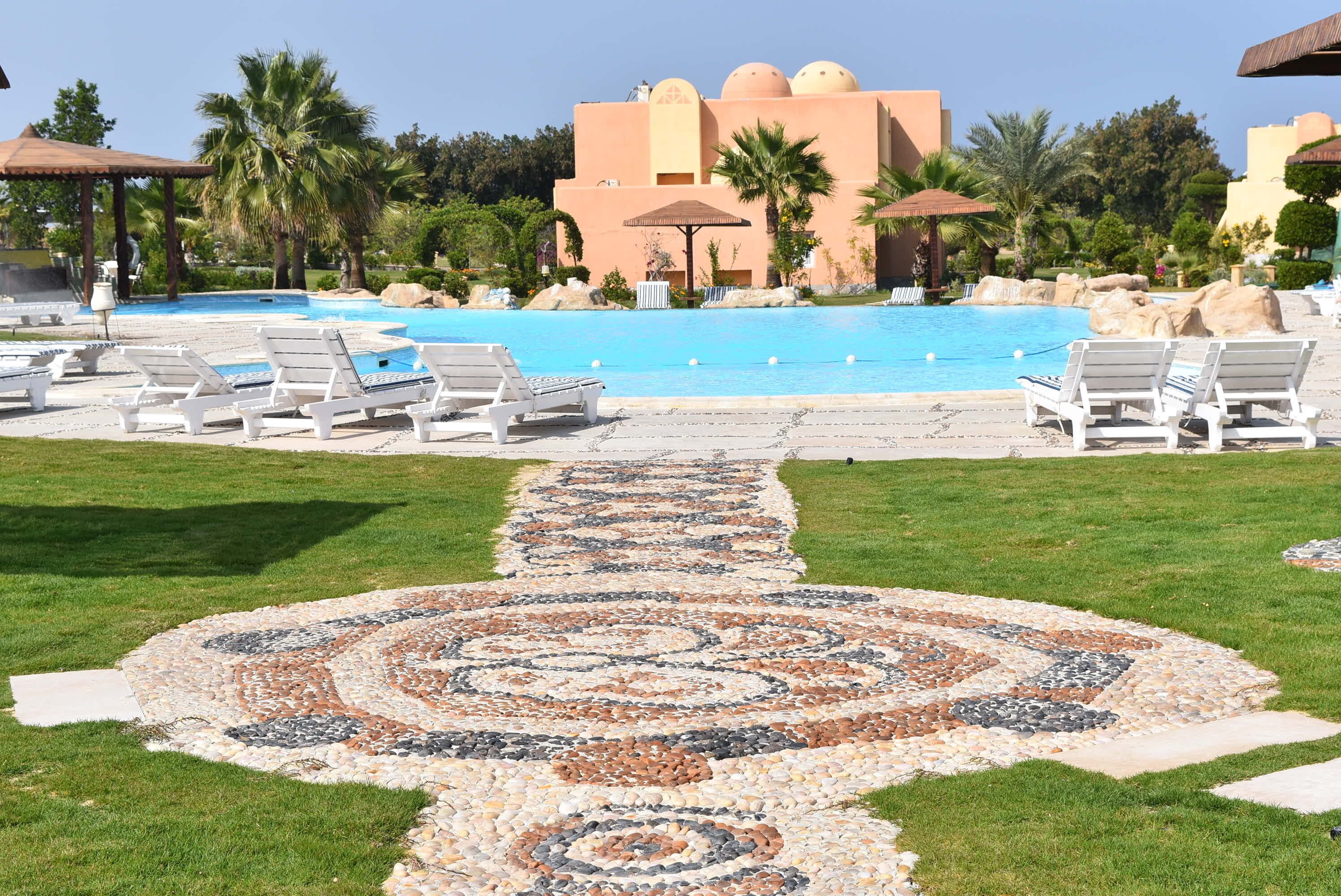 A pool area with lounge chairs, a patterned walkway, and a building with domed architecture.