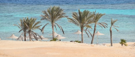 Een privéstrand, ligstoelen aan het strand, parasols, strandlakens