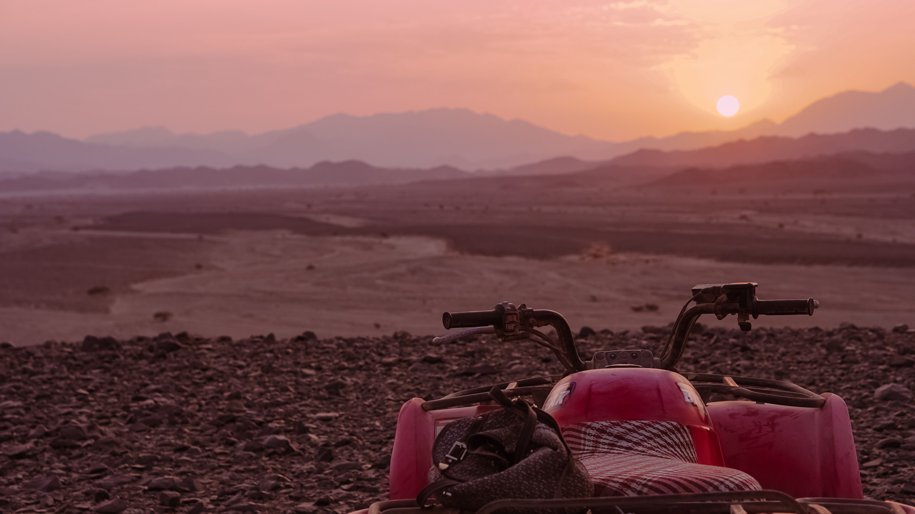 A quad bike on a rocky terrain with a sunset in the background.
