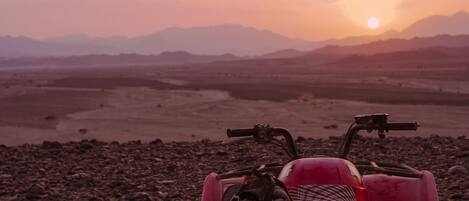A quad bike on a rocky terrain with a sunset in the background.