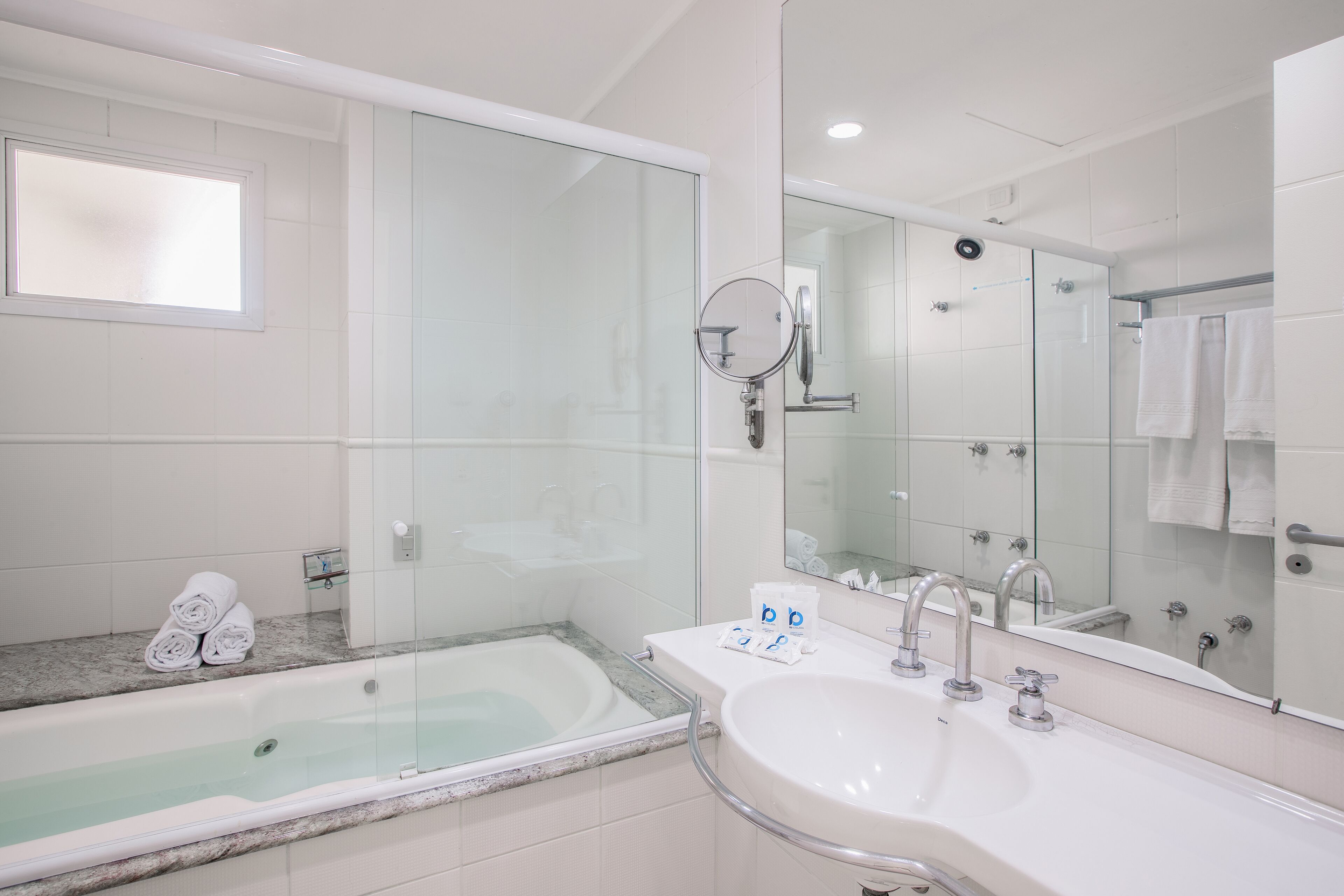 A modern bathroom with a bathtub, two sinks, a glass shower enclosure, and a large mirror.