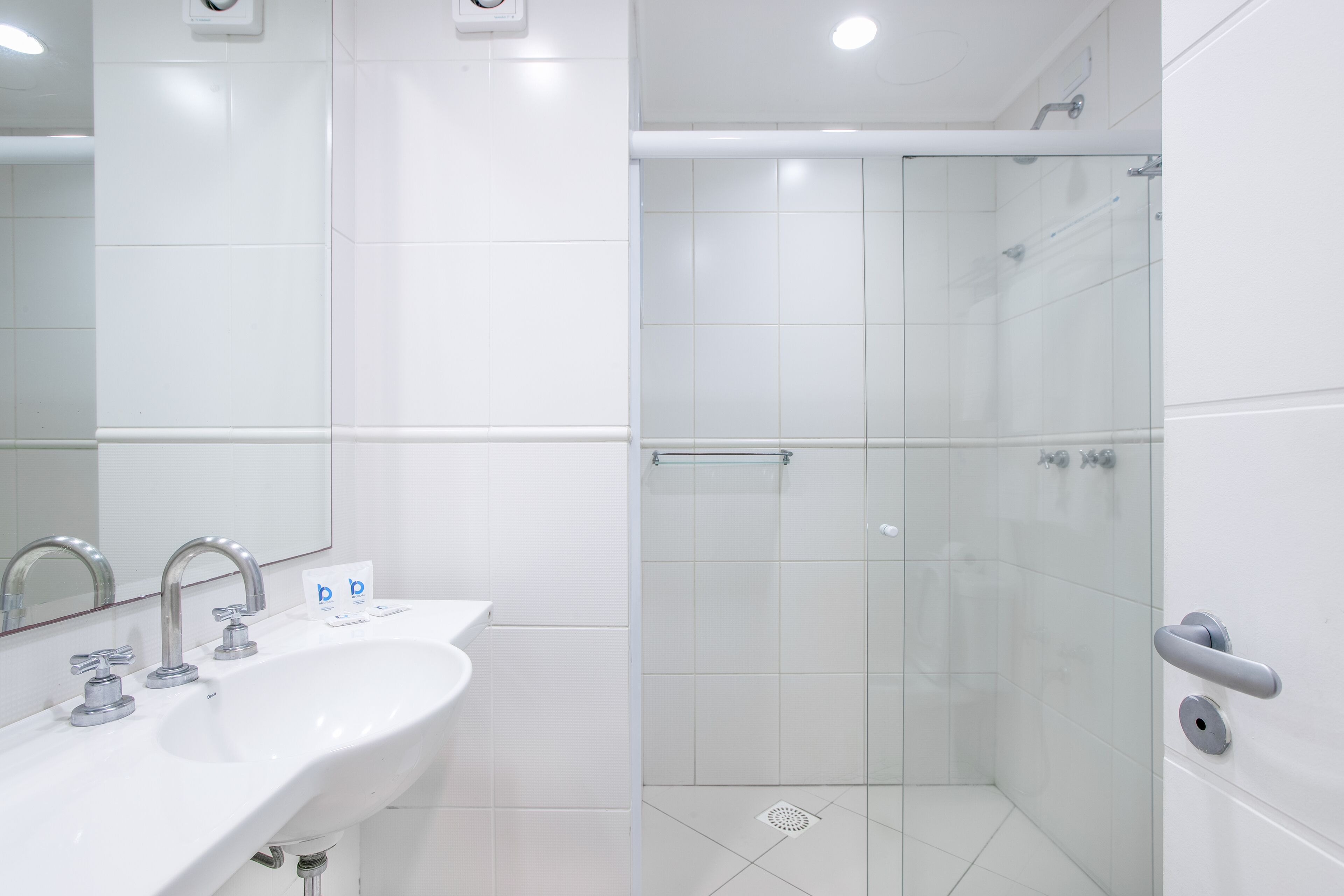 Une salle de bain moderne avec un lavabo blanc, un miroir et une cabine de douche en verre.