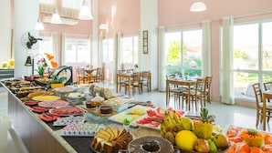 A buffet with a variety of food items, including fruits, vegetables, and pastries, in a bright room with large windows and wooden furniture. - Oceania Park Hotel Spa & Convention Center by RB Hotelaria (Florianópolis)