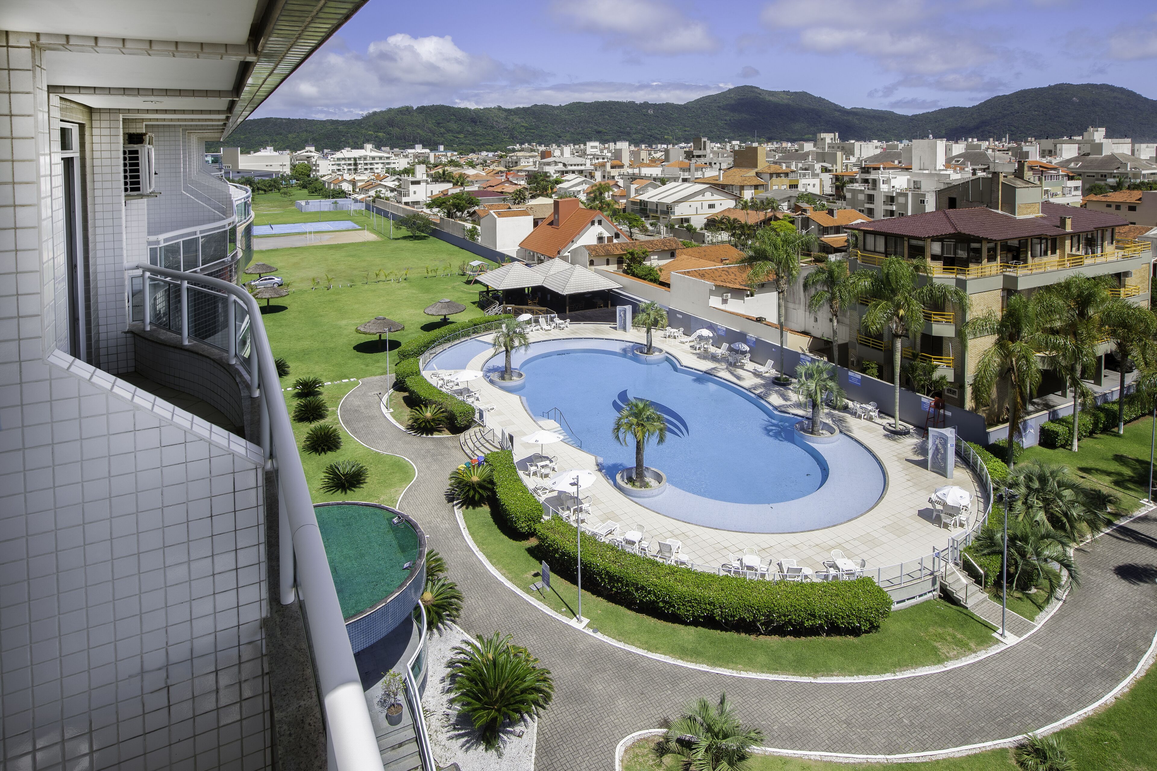 A hotel with a pool, a view of the surrounding neighborhood, and a mountain in the background.