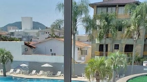 A couple in a bathtub filled with bubbles, with a pool and palm trees visible through a large window. - Oceania Park Hotel Spa & Convention Center by RB Hotelaria (Florianópolis)