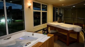 A spa room with a large bathtub, wooden bench, and a table with towels. - Oceania Park Hotel Spa & Convention Center by RB Hotelaria (Florianópolis)