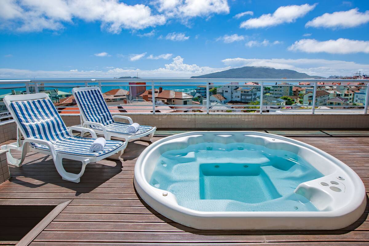 Eine Terrasse mit zwei gestreiften Liegestühlen und einem Whirlpool.