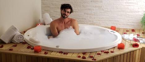 Una persona en un jacuzzi con pétalos de rosa esparcidos.