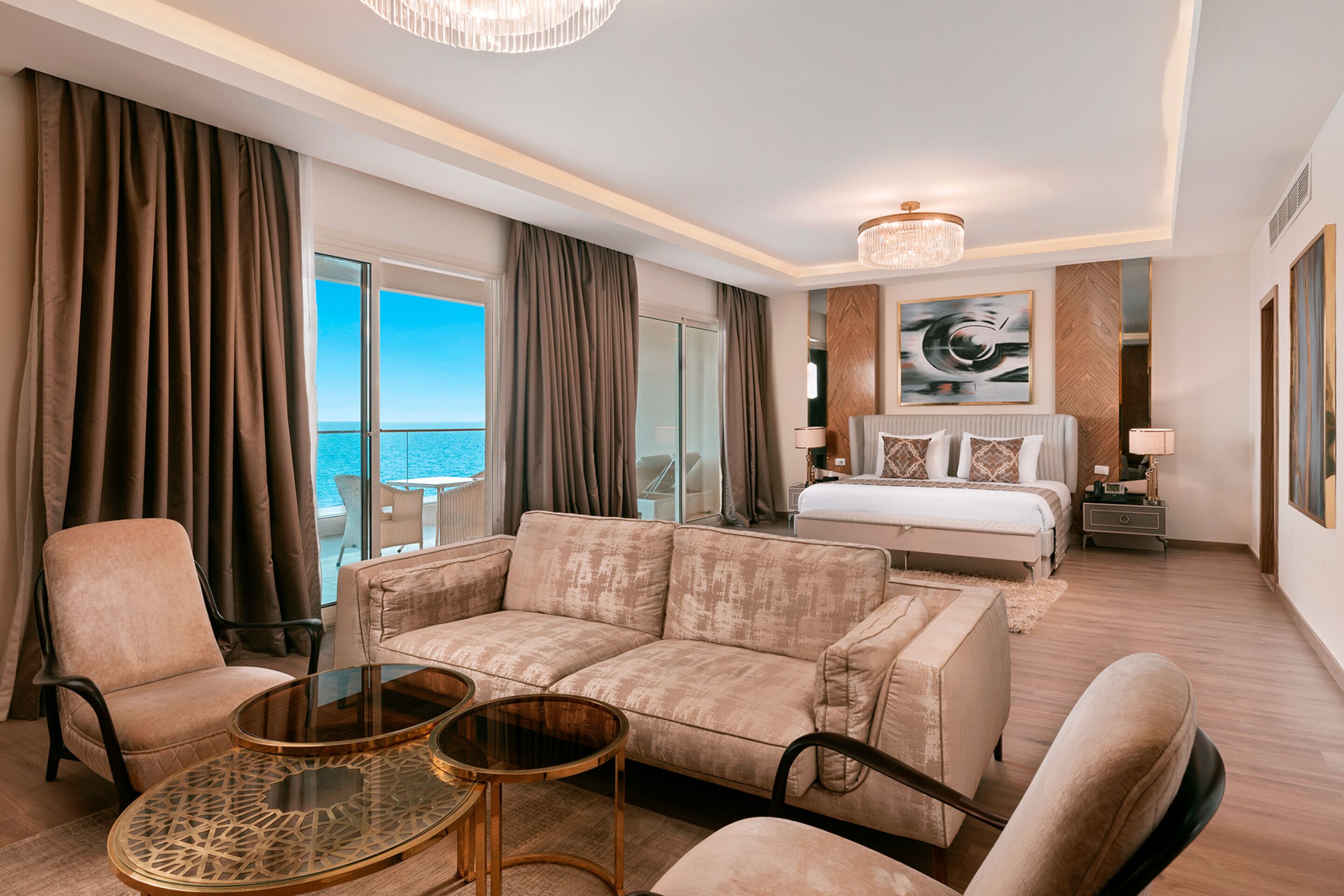 A hotel room with a large bed, a sofa, a coffee table, and a view of the ocean.