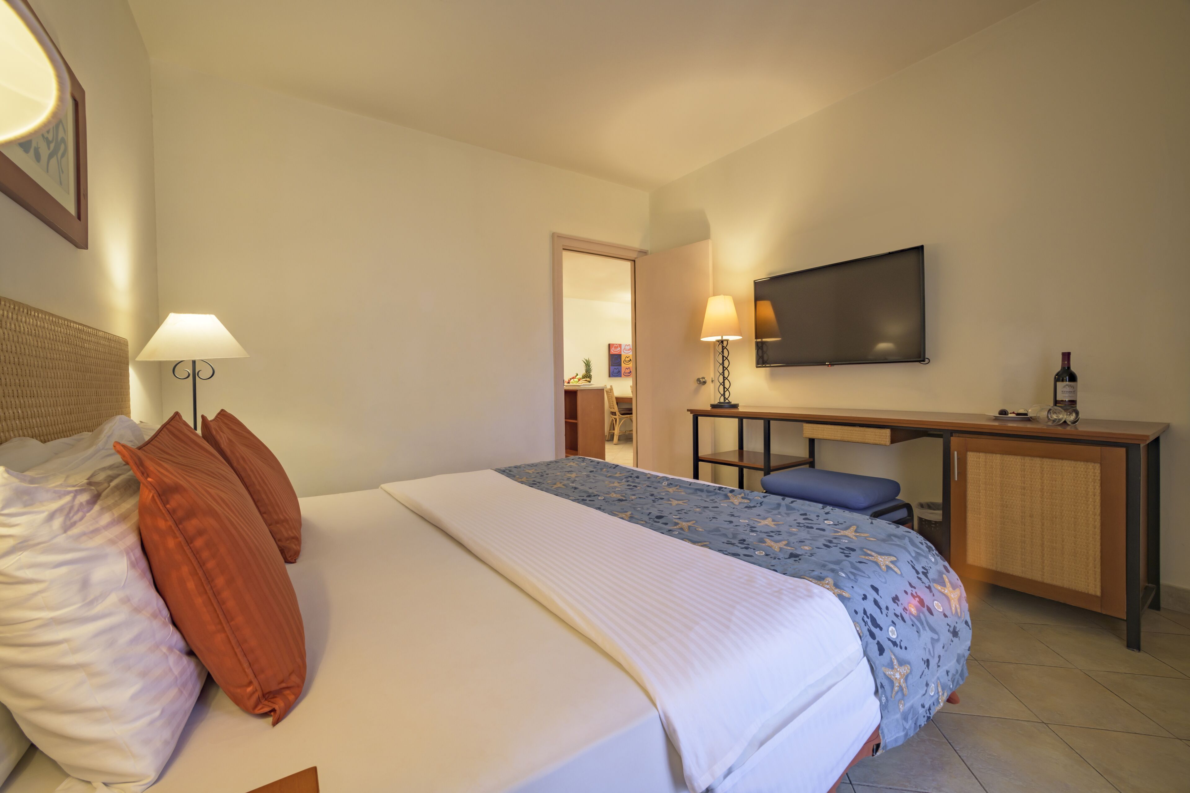 Une chambre d’hôtel avec un lit, un bureau, une télévision et une lampe.