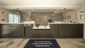 Un área de recepción con dos mostradores, un quiosco digital y una mesa de recepción.
