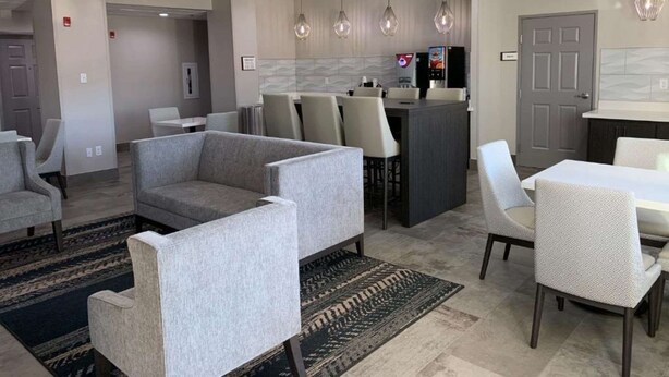 Un área de estar moderna con sofás grises, una mesa de comedor y una cocina con barra.