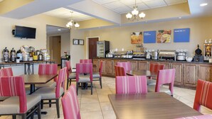 A restaurant with booths and tables, a counter with a coffee machine, and a television mounted on the wall. - Comfort Inn & Suites Lumberton Central I-95 (Lumberton)