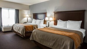 Une chambre d’hôtel avec deux lits, chacun doté d’une tête de lit en bois, de lampes de chevet et d’une fenêtre avec des rideaux.