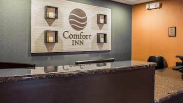 A reception desk with a sign for Comfort Inn, a counter, and a wall-mounted light fixture.